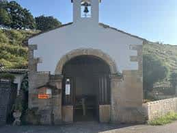 Vista frontal de la Capilla de San Esteban del Mar en Gijón, mostrando su entrada con arco de piedra y campanario