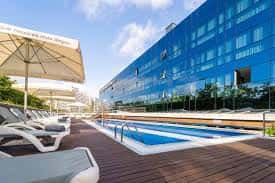Piscina exterior del hotel con tumbonas y vista del edificio