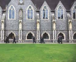 Fachada gótica del edificio principal con estudiantes caminando frente al césped