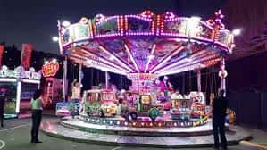 Atracción de carrusel iluminada con luces de colores durante la noche en el recinto ferial