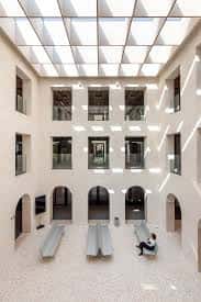 Interior del patio con claraboya, arcos y bancos modernos en el suelo de piedra