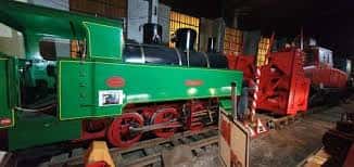 Locomotora verde y maquinaria roja en exhibición dentro del museo