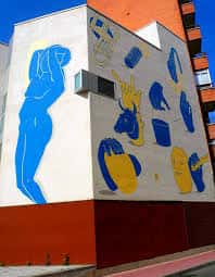 Fachada lateral del edificio con mural artístico de figuras en azul y amarillo