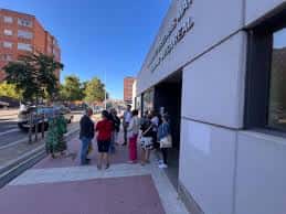 Entrada principal del centro con personas esperando bajo el porche en un día soleado