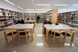 Interior de la biblioteca del centro cívico con mesas de lectura y estanterías