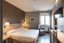 Habitación doble moderna con cama, escritorio y vista a la calle