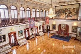 Gran salón principal de la Academia de Caballería con suelo de madera pulida y galería superior