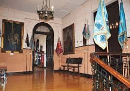 Pasillo interior con banderas militares y retratos enmarcados en las paredes