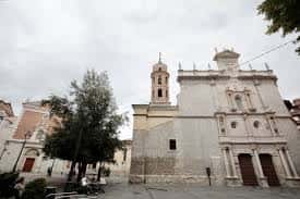 Fachada principal de la iglesia de El Salvador en la plaza, con cielo nublado y árboles a los lados