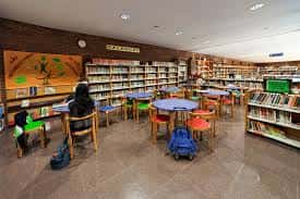Interior de la biblioteca del centro cívico con estanterías y mesas de lectura