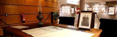 Exposición interior del museo con escritorio histórico y documentos enmarcados