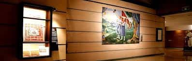 Pintura mural histórica en pared de madera con vitrina lateral