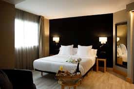 Habitación doble moderna con cama king-size, paredes oscuras y decoración elegante