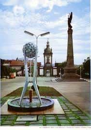 Plaza de Galicia con escultura moderna y monumento histórico al fondo