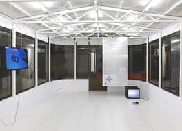 Interior del espacio de exposición con paredes blancas y techo de estructura metálica