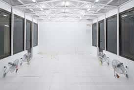 Espacio de exposición con ventiladores en el suelo y paredes blancas