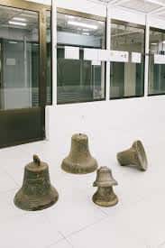 Instalación artística con campanas de bronce en el suelo del espacio de exposición