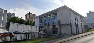 Exterior del Centro Cívico de Caranza desde la calle, con vehículos estacionados y entorno urbano alrededor