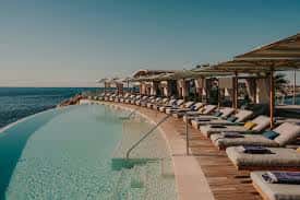Terraza con piscina infinita y hamacas frente al mar en el Lobster Club