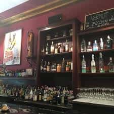 Estantería de licores con carteles decorativos y copas apiladas en el mostrador