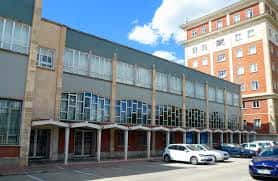 Fachada lateral del centro cívico con estacionamiento y edificios adyacentes