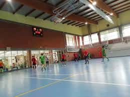 Pabellón deportivo interior con cancha de baloncesto y jugadores en actividad