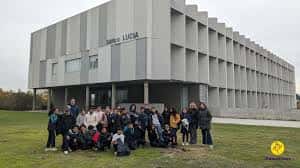 Grupo de personas posando frente al edificio moderno de la Facultad de Educación