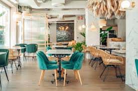 Sala principal con mesas y sillas de diseño en tonos verdes y madera
