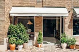 Fachada exterior del restaurante con toldo blanco y plantas en macetas