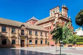 Fachada principal del colegio junto a la iglesia de Triana bajo cielo despejado
