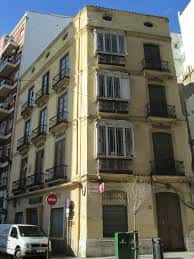 Fachada de un edificio residencial de color amarillo con balcones tradicionales