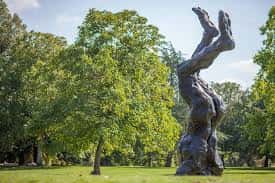Escultura artística en el jardín con árboles verdes al fondo