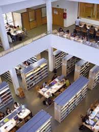 Interior de la biblioteca con estanterías, mesas de estudio y usuarios en diferentes niveles