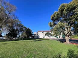 Fachada del colegio rodeada de árboles y césped bajo cielo despejado