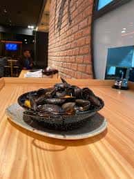 Interior del restaurante con mesa de madera y plato de mejillones