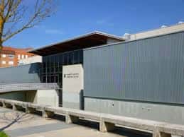 Vista exterior del Polideportivo Ariznabarra con fachada moderna y cielo despejado