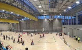 Interior del polideportivo con pista de baloncesto y actividad deportiva en curso