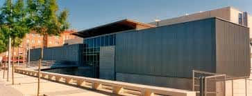 Fachada lateral del Polideportivo Ariznabarra con árboles y acceso peatonal