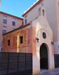 Vista exterior de la Capilla de la Piedad en Málaga con fachada de ladrillo y arco de entrada