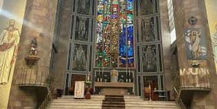 Interior de la Parroquia de San José Obrero con vitrales coloridos y altar central