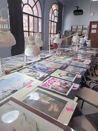 Exposición de trabajos artísticos en el interior de la ESAD con mesas y lámparas de estudio