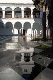 Patio exterior del CICUS con reflejos en el suelo mojado y arquería tradicional