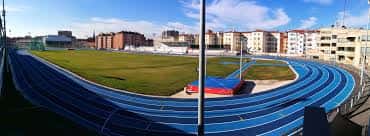 Vista panorámica desde las gradas del estadio con pista de atletismo y campo de césped
