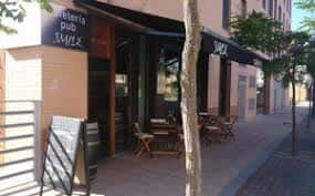 Fachada exterior de la Cafetería Pub Smile en Vitoria con mesas al aire libre