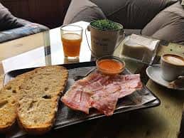 Plato de tapas con jamón, pan y bebidas en el interior del establecimiento