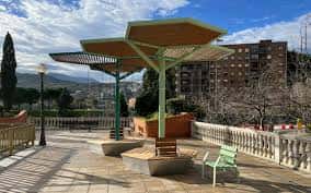 Estructura de sombra moderna en la plaza con bancos y vistas a la ciudad