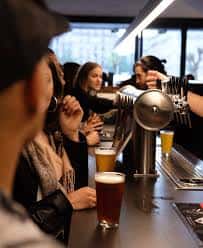 Vista del bar con grifos de cerveza y clientes bebiendo en el mostrador