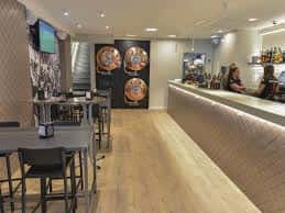 Área de barra y mesas con iluminación cálida en el Bar Campus