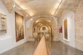 Galería de exposiciones del Museu de Mallorca con bóvedas de piedra y obras de arte en las paredes