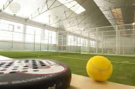 Interior de pista de pádel con pelota y raqueta en primer plano